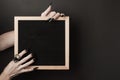 Halloween mock up. Letter board in hands with long black nails and spider ring on black background. Front view