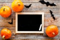 Halloween mockup. Chalkboard near paper bats and pumpkins on wooden background top view