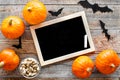 Halloween mockup. Chalkboard near paper bats and pumpkins on wooden background top view