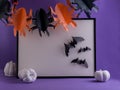 Halloween mockup with the frame, black paper bats, and white decorative pumpkins on a purple background