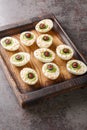 Halloween Monster eyes deviled Eggs stuffed with avocado cream wooden tray. vertical