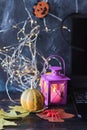 Halloween mystical decor, lantern with burning candle, autumn leaves on a black background, decorated home interior for the holida Royalty Free Stock Photo