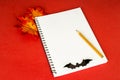 Halloween notepad. Red background. Pencil, blank note sheet, maple leaves and a bat. Blank for an invitation to halloween. Copy sp