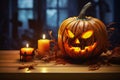 Halloween, orange pumpkin with carved face, candles and autumn leaves on wooden table with blurry background