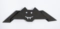 Halloween origami - black paper bat with eyes and teeth on a white background