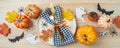 Halloween party banner concept with plate, pumpkin and decorations on wooden background. Top view, flat lay