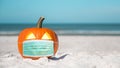 Halloween party on the beach. Carved Pumpkin Jack-o`-lantern with Medical face Mask. Jack o lantern for Happy Halloween. Autumn se Royalty Free Stock Photo