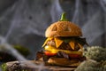 Halloween party burger in shape of scary pumpkin on a natural wooden board on dark background. Scary Halloween food concept. Royalty Free Stock Photo