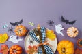 Halloween party concept with plate, pumpkin and decorations on purple background. Top view, flat lay