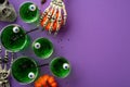 Halloween party concept. Top view photo of green floating eyeball punch spiders straws skull skeleton hands holding pumpkin