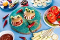 Halloween party food. Stuffed peppers with scary faces, cheese witches brooms, monster hamburgers, witch finger treats. Royalty Free Stock Photo