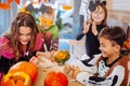 Four children attending Halloween celebration coloring pumpkins together