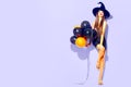 Halloween party girl. witch holding black and orange air balloons