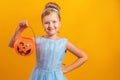 Halloween party. Little girl in a princess costume on a yellow background.