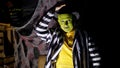 Halloween party, night, twilight, in the rays of light, a man with a terrible make-up, with a green face and a hat lifts