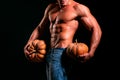 Halloween party poster or greeting card. Shirtless athletic man hold pumpkin turned back on black background. Royalty Free Stock Photo