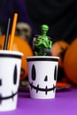 Halloween party. Skeleton covered in green slime coming out from the cup with balloons and skull in the background
