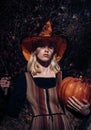 Halloween party. Halloween Witch with a carved Pumpkin and knife. Halloween Witch in magic hat with Pumpkin and knife. Royalty Free Stock Photo