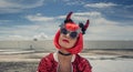 Halloween. Portrait of a beautiful girl in a red wig with horns close-up against a blue sky. Sitting on the foof. Red Royalty Free Stock Photo