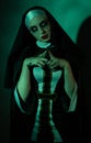 Halloween. Portrait of a scary devilish nun eyes looking at camera on a black and green background. Royalty Free Stock Photo