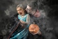 Halloween portrait, vampire attacking young princess, man holding small pumpkin smoke background Royalty Free Stock Photo