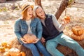 Halloween Preparaton Concept. Young couple sitting at garden with pumpkins laughing cheerful