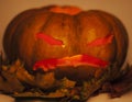 halloween pumpkin with autumn yellow dry leafes, scary angry face close up, post card concept