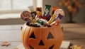 Halloween pumpkin bucket filled with assorted candies on table Royalty Free Stock Photo
