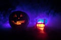 Halloween pumpkin with carved face and glass of whiskey with ice on a dark toned foggy background with zombies. Decorated. Royalty Free Stock Photo