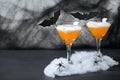 Halloween Pumpkin Cocktail, Toxic Orange Drink Decorated with Spiders, Cobweb and Black Bats on Dark Background