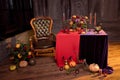 Halloween pumpkin decor with candles and a bouquet of flowers in a bronze vase on a red tablecloth.