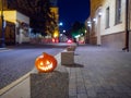 Halloween pumpkin on a deserted city street at night. Blurry colored city lights and old high-rise buildings Royalty Free Stock Photo