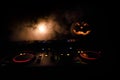 Halloween pumpkin on a dj table with headphones on dark background with copy space. Happy Halloween festival decorations and music