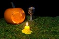 Halloween pumpkin, goblet and candles glowing in the dark on a f