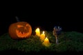 Halloween pumpkin, goblet and candles glowing in the dark on a f