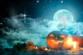 Halloween pumpkin Jack-o'-lantern on wooden table with candles in a spooky night over moon and clouds Royalty Free Stock Photo