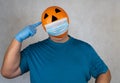 Halloween pumpkin in a medical respiratory bandage face. Surgical protective mask. person with orange evil mask Royalty Free Stock Photo