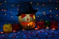 Halloween pumpkin in mystical shadow, peppers with curved faces, candies, bokeh effect lights, window sill