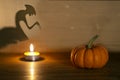 Halloween pumpkin on old wooden background. Spirit monster behind. Shadow theatre concept