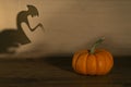 Halloween pumpkin on old wooden background. Spirit monster behind. Shadow theatre concept