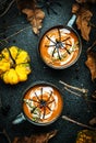 Halloween pumpkin soup with cream and .thyme. Autumn festive vegan vegetarian food. Soup mug on black background with fallen oak