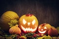 Halloween pumpkins glow, carved jack-o-lantern in fall leaves