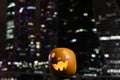 Halloween Pumpkins head. Orange pumpkin with a smile and eyes on night city and lights background Royalty Free Stock Photo