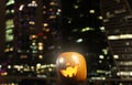 Halloween Pumpkins head. Orange pumpkin with a smile and eyes on night city and lights background Royalty Free Stock Photo