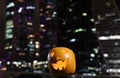 Halloween Pumpkins head. Orange pumpkin with a smile and eyes on night city and lights background Royalty Free Stock Photo