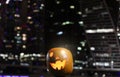 Halloween Pumpkins head. Orange pumpkin with a smile and eyes on night city and lights background Royalty Free Stock Photo