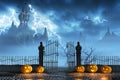 Halloween pumpkins next to a gate of a spooky castle