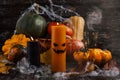 Halloween pumpkins, spiders, web and autumn leaves. An orange candle with a scary face and dark candles as decor. Royalty Free Stock Photo