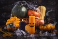 Halloween pumpkins, spiders, web and autumn leaves. An orange candle with a scary face and dark candles. Royalty Free Stock Photo