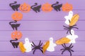 Halloween round frame with different paper silhouettes of pumpkins, cats, ghosts and spiders with autumn leaves